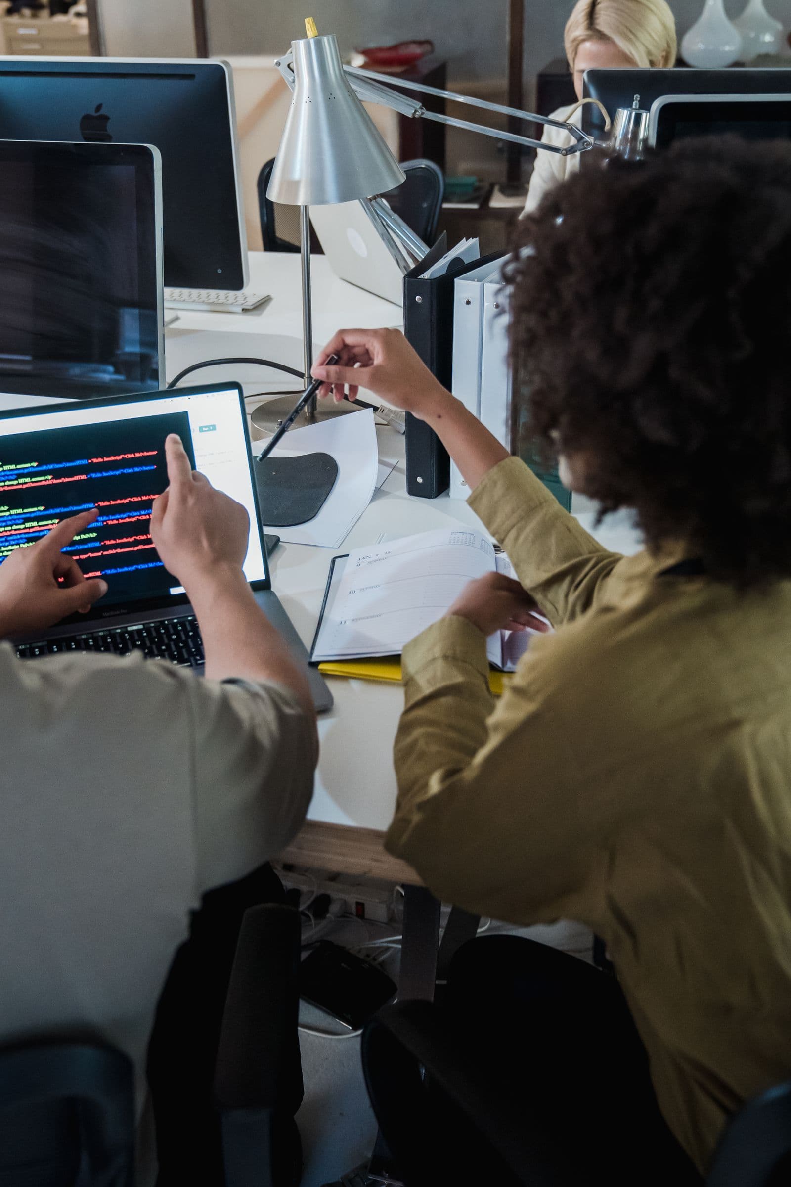 Une équipe de développeurs vue de dos, penchée sur du code