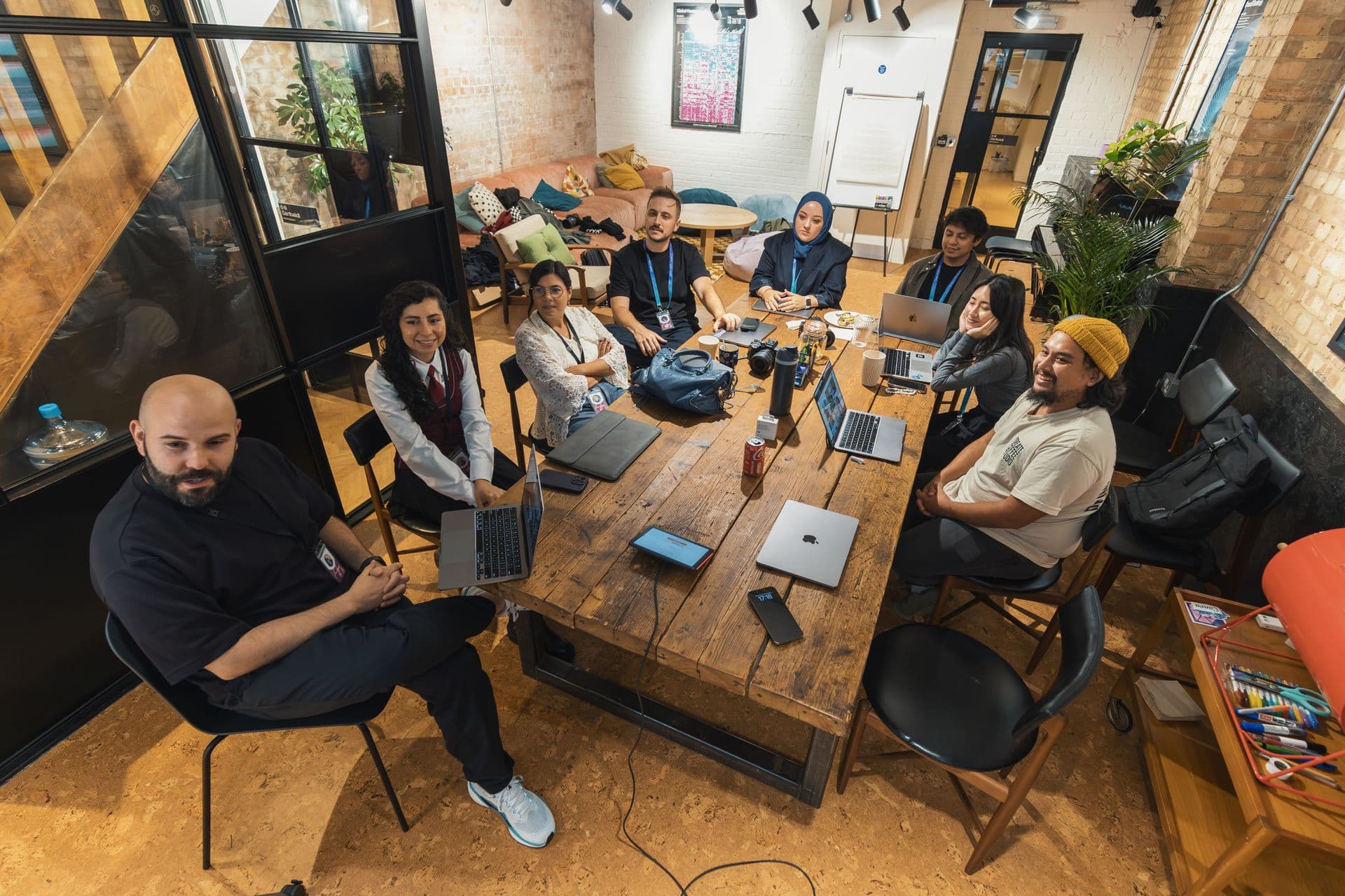 Des membres de Chantier autour d’une table, ordinateurs ouverts, dans un atelier en briques
