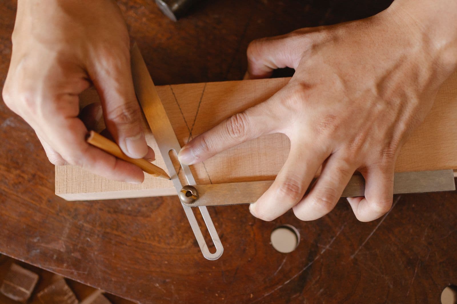 Des mains qui mesurent et tracent sur une planche de bois